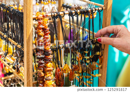 Amber beads in a street shop. The hand in the frame selects amber beads. Souvenir the Baltic Sea Amber beads in a street shop. The hand in the frame selects amber beads. Souvenir the Baltic Sea 125291817