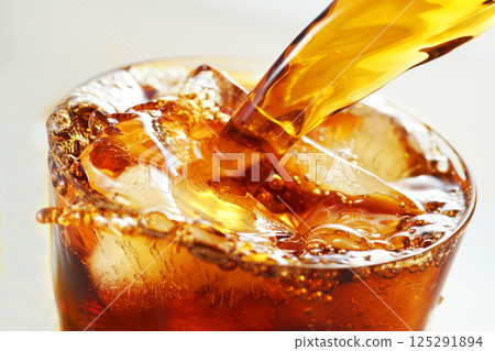 Iced coffee being poured vigorously into a glass 125291894