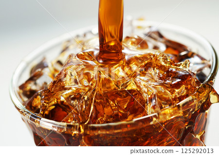 Iced coffee being poured vigorously into a glass 125292013