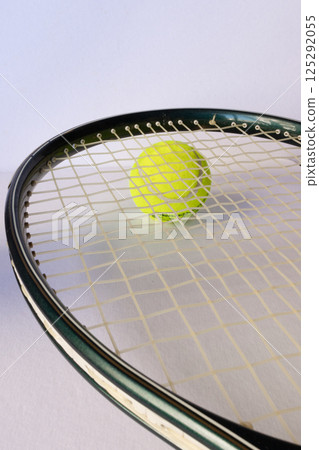 Vertical photo of a tennis racket on a ball. Light background 125292055