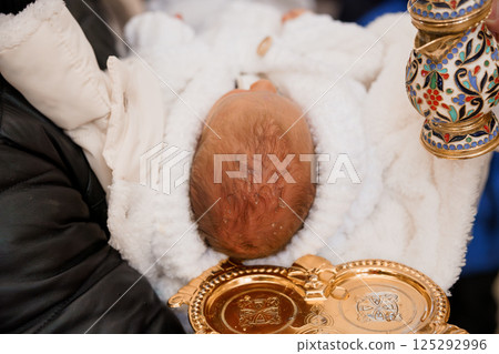 Newborn Baby Being Held with Decorative Baptismal Items 125292996
