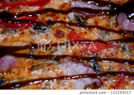 Close-up shot of sliced pizza with red pepper, mushrooms, and ham, showcasing the cheesy texture and delicious toppings in vibrant colors 125293017