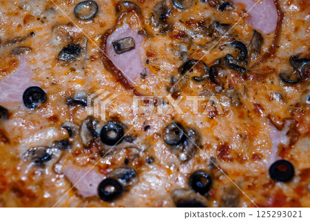 Delicious close-up of a pizza with ham, mushrooms and black olives on melted cheese, showcasing vibrant colors and appetizing texture Delicious close-up of a pizza with ham, mushrooms and black olives on melted cheese, showcasing vibrant colors and appetizing texture 125293021