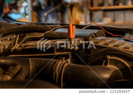 Car Battery Maintenance with Jumper Cables in a Garage Setting 125293057
