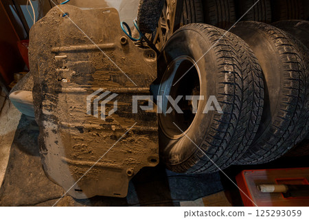 Vehicle Maintenance: A Close-Up of Used Tires and a Mud-Covered Undercarriage Shield Vehicle Maintenance: A Close-Up of Used Tires and a Mud-Covered Undercarriage Shield 125293059