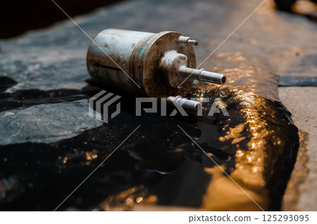 Rusty Automotive Fuel Pump on Oil-Stained Floor 125293095