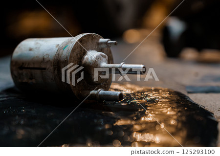 Rusty Fuel Filter on a Dark Garage Floor with Oil Puddle 125293100