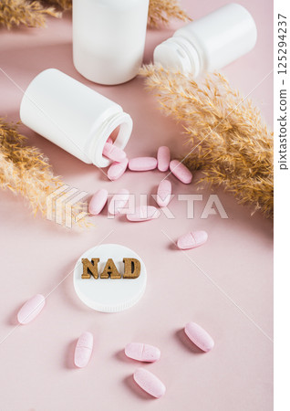 NAD+ molecule in pills for anti-aging and biohacking on pink background vertical view 125294237