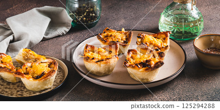 Mini tartlets with caramelized onions and cheese on a plate on a table web banner Mini tartlets with caramelized onions and cheese on a plate on a table web banner 125294288
