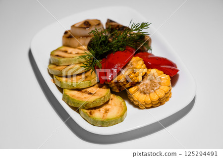 Grilled vegetables assortment on a white plate, including zucchini, onion, red pepper and corn with fresh dill garnish Grilled vegetables assortment on a white plate, including zucchini, onion, red pepper and corn with fresh dill garnish 125294491
