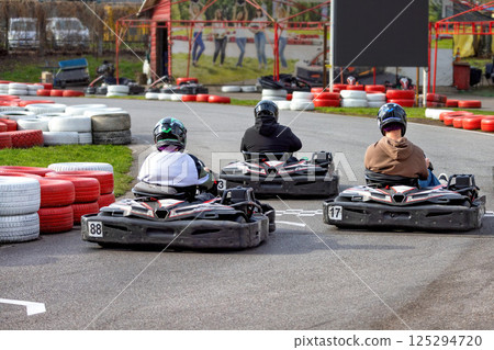 Racing excitement at a karting circuit on a bright day with friends enjoying the thrill together Racing excitement at a karting circuit on a bright day with friends enjoying the thrill together 125294720