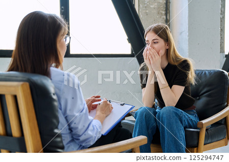 Sad upset young woman patient in therapy session in psychologist office Sad upset young woman patient in therapy session in psychologist office 125294747