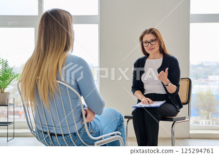 Middle aged female psychologist, therapist working with woman patient 125294761