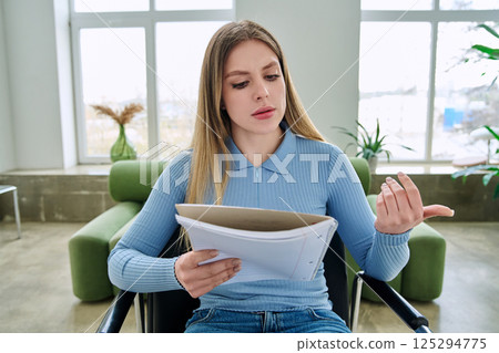 Webcam view young female student with textbook in hands, sitting at home Webcam view young female student with textbook in hands, sitting at home 125294775