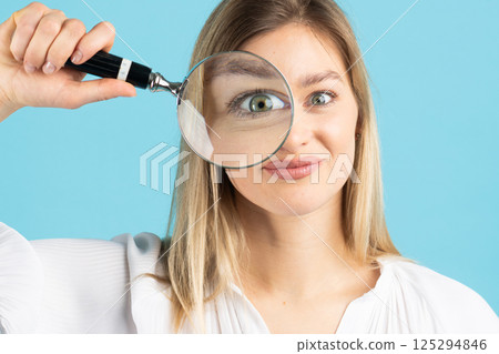 Studio portrait of woman with magnifying glass Studio portrait of woman with magnifying glass 125294846