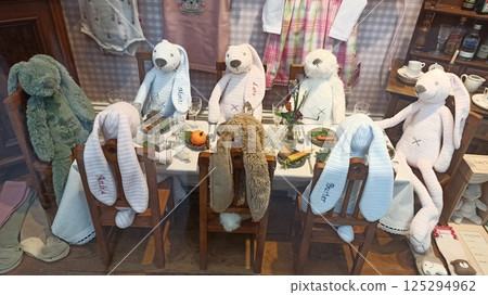 A group of plush bunnies sit around a fully set dining table in a whimsical shop display resembling a festive family meal. The image conveys playfulness, imagination and Easter-themed storytelling A group of plush bunnies sit around a fully set dining table in a whimsical shop display resembling a festive family meal. The image conveys playfulness, imagination and Easter-themed storytelling 125294962