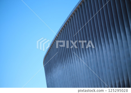 Cladding of a modern sports stadium against a blue sky 125295028