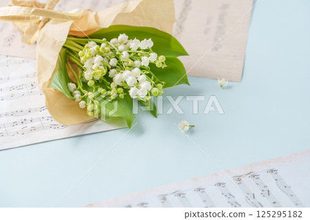 Natural lily of the valley bouquet and sheet music | Blue background 125295182