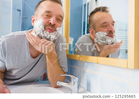 Guy shaving his beard in bathroom 125295665