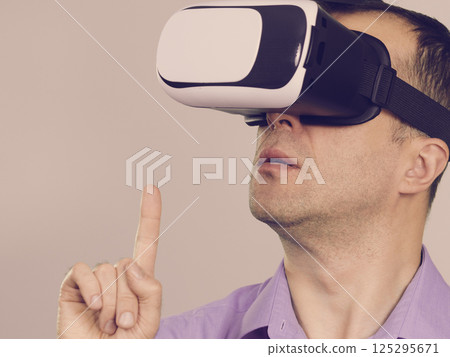 Man wearing virtual reality goggles on grey Man wearing virtual reality goggles on grey 125295671