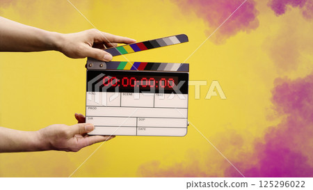 Digital film slate for filmmaker in set. Hand hitting timecode clapperboard or movie slate for Video Production. Digi number clapper board or film slates action on set. Tools in modern cinema industry 125296022