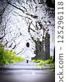 A girl walking through a cherry blossom arch 125296118