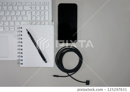 Flat lay on white background top view with copy space. Computer laptop keyboard, notebook, smartphone and cable. The concept of business, study or IT Flat lay on white background top view with copy space. Computer laptop keyboard, notebook, smartphone and cable. The concept of business, study or IT 125297631