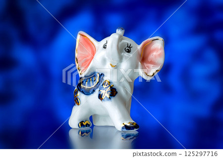 porcelain statuette, porcelain statuette of the elephant on a blue background porcelain statuette, porcelain statuette of the elephant on a blue background 125297716