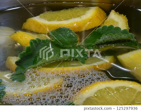 Homemade lemonade. Orange, lemon and mint pieces in a large container with spring water. Close-up 125297936