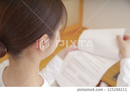 Woman looking at documents in the living room Woman looking at documents in the living room 125298211