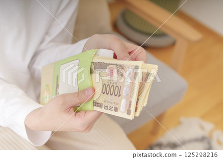 Woman holding money in an envelope 125298216