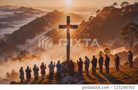 Group of people are gathered around a cross on a hillside. The scene is peaceful and serene, with the sun shining through the mist and the people standing in a circle. The cross is a symbol of faith 125298302