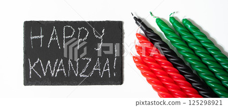 Happy Kwanzaa concept. Afro-American holiday. Congratulatory lettering and seven candles - red, black and green. African heritage symbol on white background. Happy Kwanzaa concept. Afro-American holiday. Congratulatory lettering and seven candles - red, black and green. African heritage symbol on white background. 125298921
