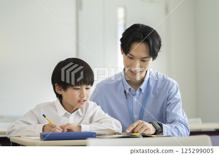 一名四年級男孩正在和老師一起學習 125299005