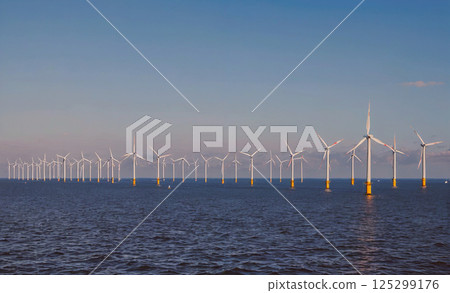 Long line of wind turbines are in the water. The wind turbines are in the water and are very tall 125299176