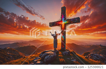 Man is standing on a mountain with a cross in front of him. The sky is orange and the mountains are in the background 125300021