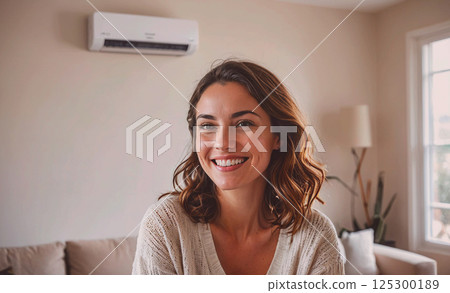 Woman with brown hair is smiling and sitting on a couch. The room has a white wall and a window Woman with brown hair is smiling and sitting on a couch. The room has a white wall and a window 125300189