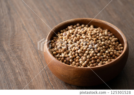 Coriander seeds (whole) in a wooden container Coriander seeds (whole) in a wooden container 125301528