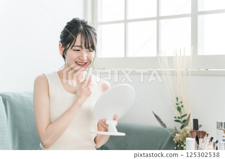 使用水去角質、毛孔護理、面部設備的年輕亞洲女性 使用水去角質、毛孔護理、面部設備的年輕亞洲女性 125302538