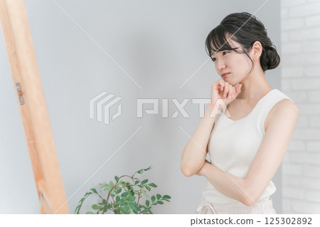 Asian woman looking at the mirror suffering from diet complex and body shape 125302892