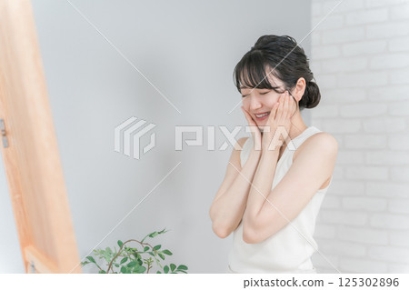 Smiling Asian woman doing skin care and moisturizing Smiling Asian woman doing skin care and moisturizing 125302896