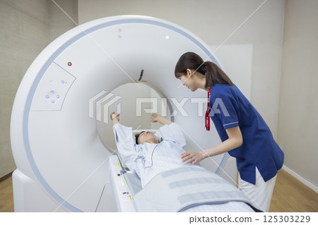A man undergoing a CT scan with a radiologist. Photo courtesy of Denpa Gakuen, Tokyo Electronics College. 125303229