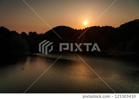 Sunset sinking into the mountains on the opposite bank. Interval photography at Nara Nunome Dam. Sunset sinking into the mountains on the opposite bank. Interval photography at Nara Nunome Dam. 125303410