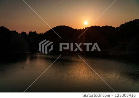 Sunset sinking into the mountains on the opposite bank. Interval photography at Nara Nunome Dam. Sunset sinking into the mountains on the opposite bank. Interval photography at Nara Nunome Dam. 125303416