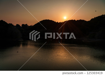 The sun setting behind the mountains on the opposite bank. Interval shots taken at Nara Nunome Dam. The sun setting behind the mountains on the opposite bank. Interval shots taken at Nara Nunome Dam. 125303419