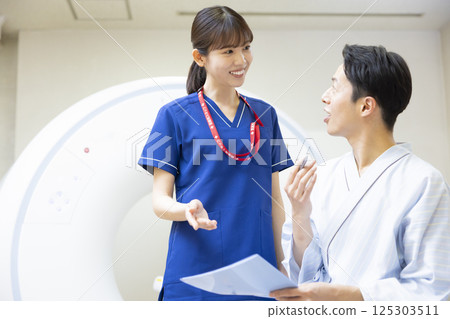 A man undergoing a CT scan with a radiologist. Photo courtesy of Denpa Gakuen, Tokyo Electronics College. 125303511
