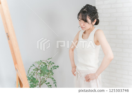 患有厭食症和體重減輕的亞洲女性看著鏡子檢查腰部 125303746