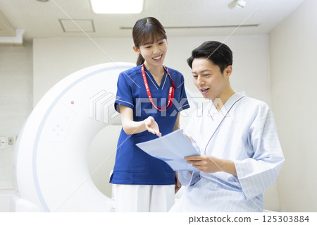 A man undergoing a CT scan with a radiologist. Photo courtesy of Denpa Gakuen, Tokyo Electronics College. 125303884