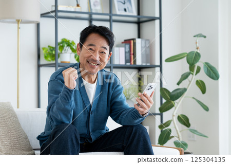 Middle-aged man using a smartphone in the living room Middle-aged man using a smartphone in the living room 125304135