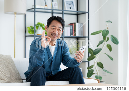 Middle-aged man using a smartphone in the living room 125304136
